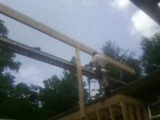 Carpenter setting a ridge beam over a new addition frame — Ice Dam Removal by Roofing Brothers in Toluca