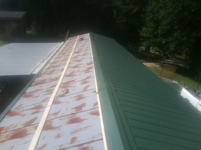 Old rusted panels beside newly installed green metal roofing — Wind Damage Roof Repair by Roofing Brothers in Toluca