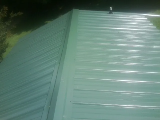 New green metal panels meeting at the ridge of a roof — Flat Roof Repair work by our crew in Toluca