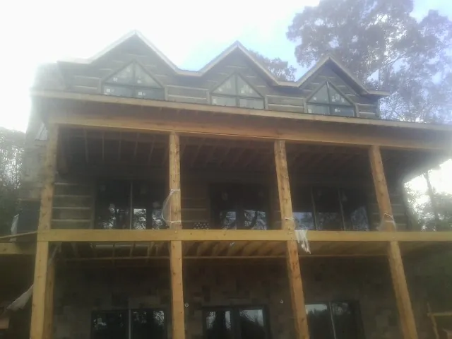 Dormers and porch framing on a large log home under construction — Roof Coating work by our crew in Toluca