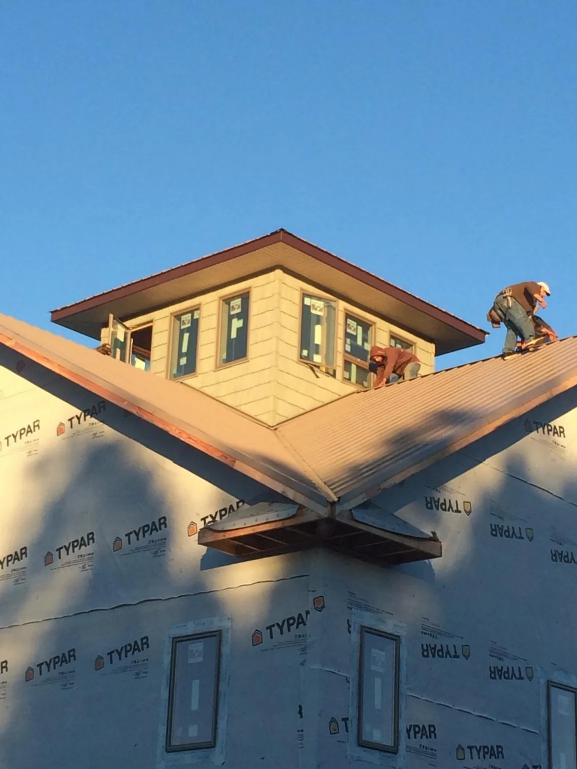 Roofers working around a rooftop cupola on a new metal roof at sunset — Roof Waterproofing in Toluca by Roofing Brothers